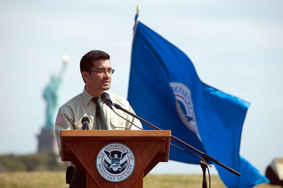 Rob speaking at a US citizenship event with the Statue of Liberty in the background.