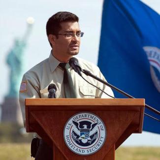 Rob speaking at a US citizenship event with the Statue of Liberty in the background.